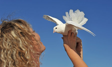 young girl and her dove on a blue skyの写真素材