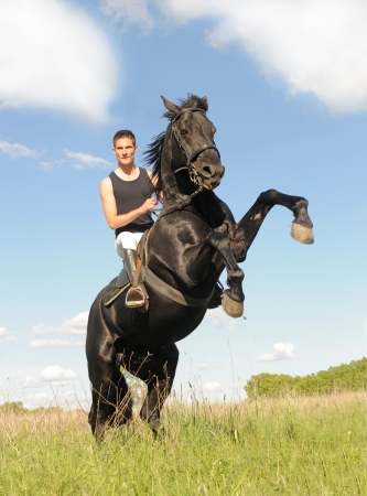 young man and her beautiful black stallion rearing upの写真素材