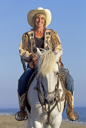cowgirl on camargue horse on the beachの写真素材