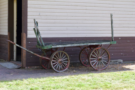 Antique weathered flat bed wooden wagon cart setting next to an old 19th century building