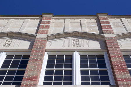 Upward view of a stately 20th Century brick and stone building with large attractive windows, with...