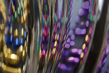 Macro view of beautiful lead crystal glass with curved rippling surface, reflecting brilliant multi colors with bokehの写真素材
