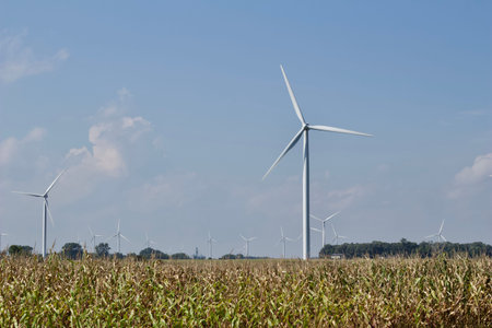 Landscape view of giant wind power turbines in crop fields, with blue sky and copy space