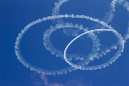 Sky view of circular vapor trails of an airplane from an air show acrobatic flight performance, with blue sky and copy spaceの写真素材