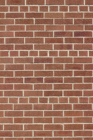 Modern reddish brown textured clay brick wall background, in a common bond brickwork pattern