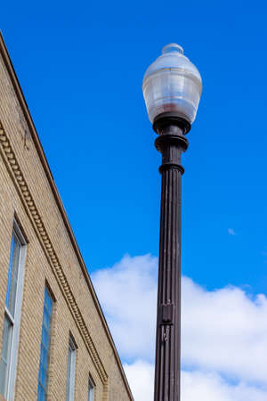 Upward view of a street light next to a vintage brick building in an urban setting, with blue sky backgroundの写真素材