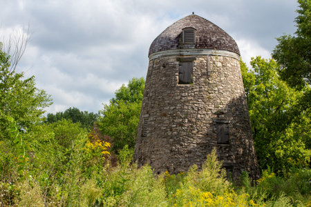 Landscape view of a 19th Century round stone constructed grain windmill preserved in a North...