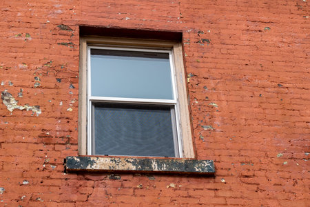 Full frame texture background of a grungy window on an old rust red color painted brick wall,...