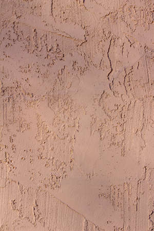 Full frame close up texture background of an attractive vintage reddish brown exterior stucco wall surface, with faint tree shadows and copy spaceの写真素材