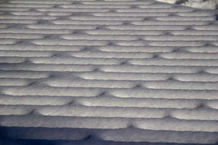 Full frame abstract texture background of fresh snow designs on a wooden deck in winter with natural sunlightの写真素材