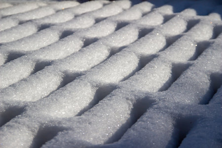 Full frame abstract texture background of fresh snow designs on a wooden deck in winter with natural sunlightの写真素材