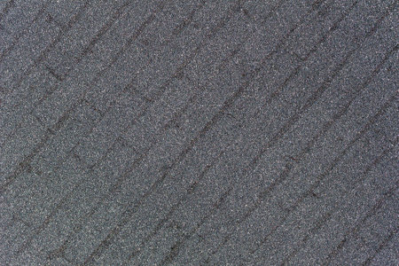 This image shows a macro abstract texture of sparkling silver glitter background with a faint...