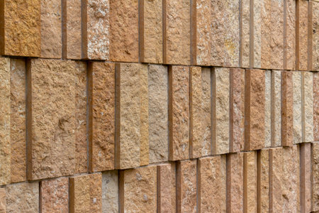 This image shows a modern style rough textured limestone brick wall background with attractive vertical aligned natural kasota stone blocks in varying widths and shades of light brown.の写真素材