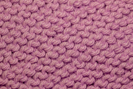 This image shows a macro abstract background of hand-knitted yarn fabric texture with a garter stitch pattern, in the color of lavender.の写真素材