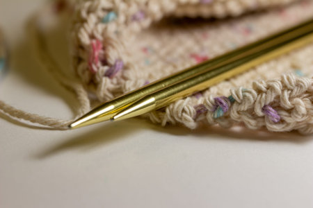 This image shows a close up defocused view of a hand knitted cotton wash cloth and a pair of metal...