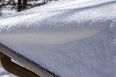 This images shows a full frame close-up abstract texture background of heavy snow on the end of a home rooftop, with copy space.の写真素材