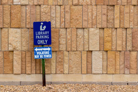 Close up view of a library parking sign in front of an attractive modern limestone wall with unique rough textured vertically aligned natural stone bricksの写真素材