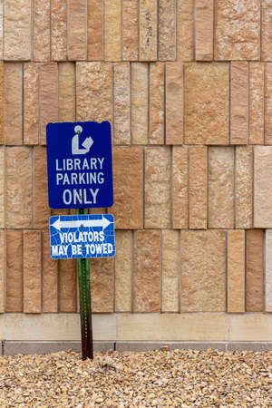 Close up view of a library parking sign in front of an attractive modern limestone wall with unique rough textured vertically aligned natural stone bricksの写真素材