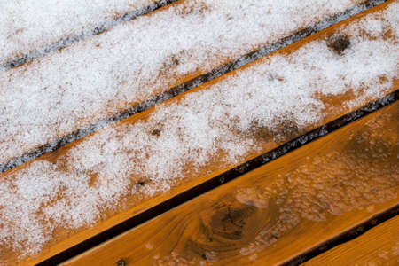 This image shows an abstract texture background of melting snow on a hardwood cedar deck in springtime.の写真素材
