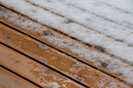 This image shows an abstract texture background of melting snow on a hardwood cedar deck in springtime.の写真素材