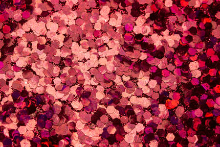 This image shows a full frame macro photographed sparkling red color glitter surface background with bokeh.の写真素材