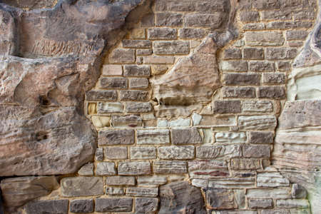 This image shows a unique texture background view of an ancient fortified stone wall surface, with some modern repair in various places.の写真素材
