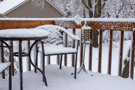 Close up view of an outdoor wooden deck with a round table and chairs, covered with thick snow during a winter blizzard.の写真素材