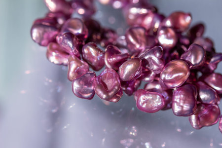 Macro abstract texture background of a deep pink color natural baroque pearl necklace with natural imperfections, on a translucent glass surface.の写真素材