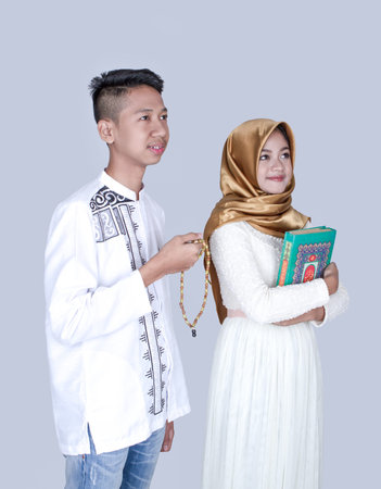 Muslim boy holding praying beads with hijab girl holding Quran