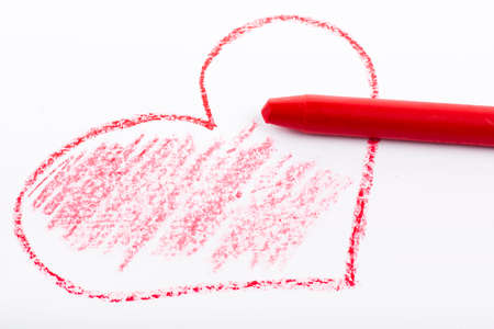 Closeup of a red pencil drawing a heart. On white paper.の写真素材