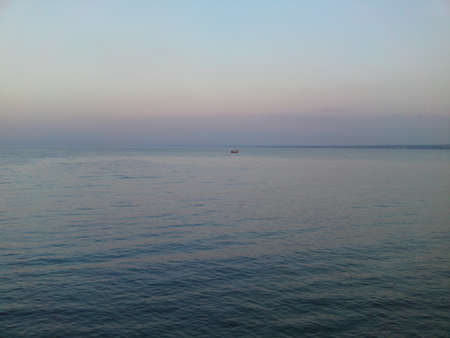 Calmness beautiful blue sea and sky with a fishing boat in the distant.の写真素材