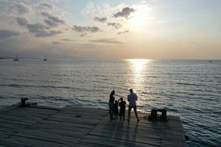 Family watches sunset on the beach in Lovina Bali Indonesiaの写真素材