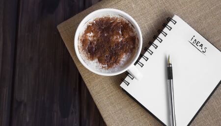 Notebook where you can write your ideas and a coffee beside so it's stimulates your creativity.の写真素材