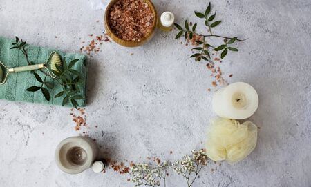 Spa necessities like bath salt, essential oils, candles, towel and flowers for a calm relaxing bath on grey surface.の写真素材