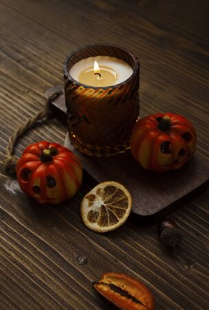 Autumnal home decor with candle, dried fruits and pumpkin on wooden background.の写真素材
