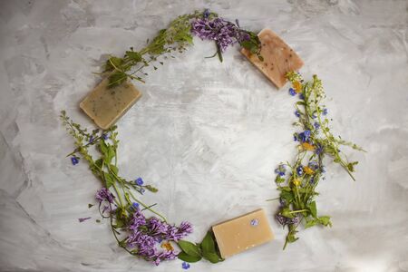 Top view of vibrant flowers and natural bar soaps arrange in a circle, on grey background.の写真素材