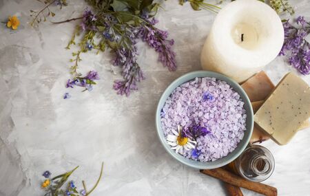 Top view of purple bath salt,herbal flowers, candle, bar soaps and oil on grey surface.の写真素材