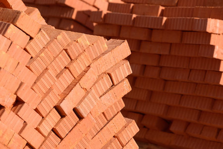Pile of stacked new red bricks. Clay brick blocks ready for construction.
