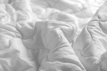 White blanket. Wrinkle messy blanket in bedroom after waking up in the morning. Bed details. Duvet and blanket, an unmade hotel bedroom with white blanket. Messy White Bed.の写真素材
