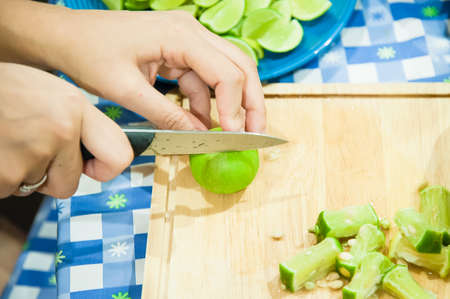Lemon slice with knife in hand on wooden boardの写真素材