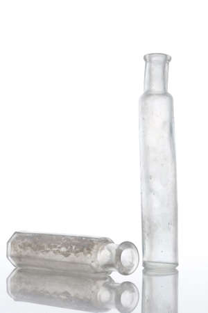 Antique bottles on white table with reflections and isolated backgroundの写真素材