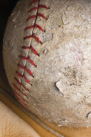 well-used softball with red stitching in mitt の写真素材