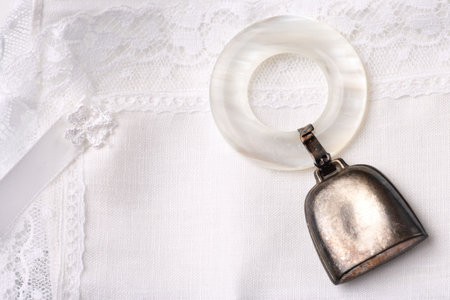 vintage baby rattle with mother of pearl ring isolated on a white linen