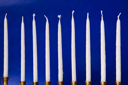 white hanukkah candles in a menorah on blue backgroundの写真素材