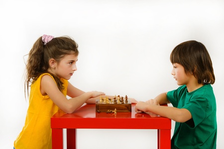 two children playing chess isolated on white backgroundの写真素材
