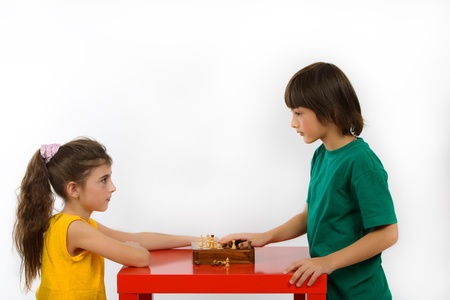 two children playing chess isolated on white backgroundの写真素材