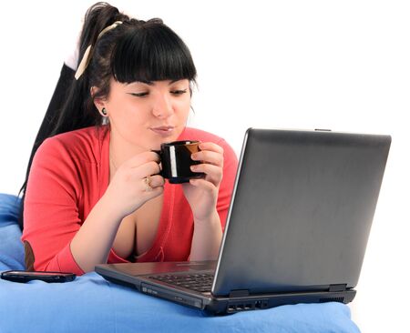young brunette woman drinking coffee in front of a notebookの写真素材