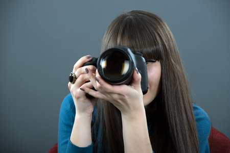 Young woman with DSLR over dark background