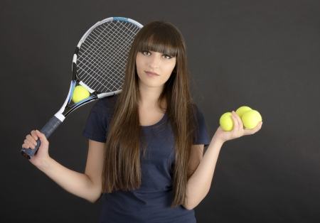 Female tennis player with racket and ball on black backgroundの写真素材