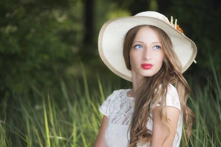 Woman in park seating on the grass with hat over her headの写真素材